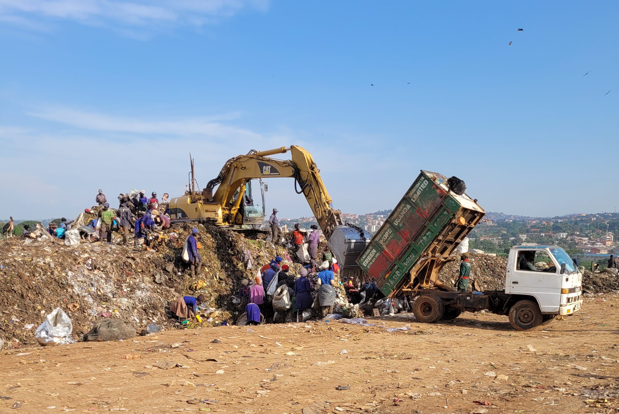 Solid waste collection trucks and excavator at work